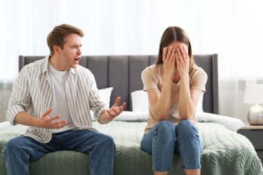 Kadın ve erkek evde yatakta kavga ediyor.