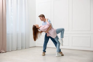 Mutlu çift evde beyaz duvarın yanında dans ediyor.