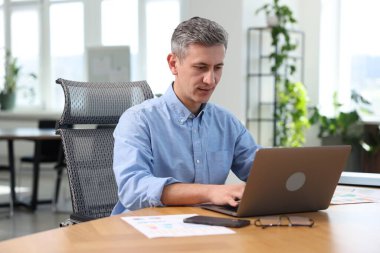 Ofiste masada dizüstü bilgisayar üzerinde çalışan işadamı