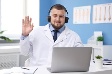 Kulaklıklı doktor içeride bilgisayarla online danışmanlık yapıyor.