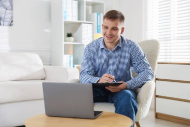 Ofisteki dizüstü bilgisayarın çevrimiçi oturumu sırasında elinde panoyla gülümseyen psikolog