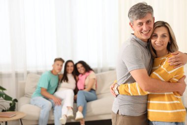 Mutlu arkadaşlar evde sarılıyor, seçici odaklanıyor.