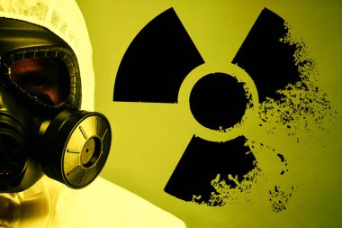 Arka planda tehlikeli madde kıyafeti ve gaz maskesi giyen bir adam. Arkasındaki radyoaktif işaret çözülüyor.