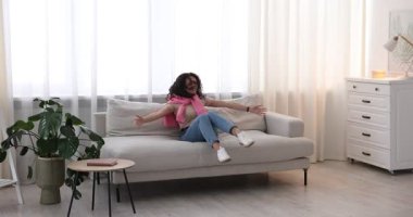 Mutlu arkadaşlar evdeki kanepede zıplayıp sarılıyorlar.