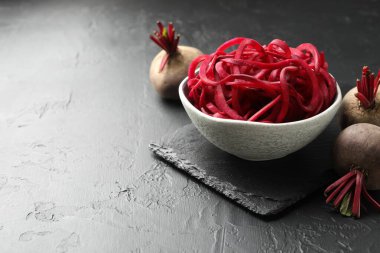 Vejetaryen yemeği. Çiğ pancar eriştesi ve taze sebzeler siyah masada, yakın plan. Metin için boşluk