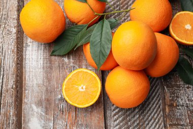 Taze portakallar ve yapraklar ahşap masada, düz yatıyordu.