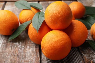 Taze portakallar ve yapraklar ahşap masada, yakın plan.