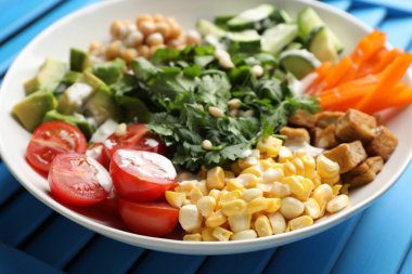 Açık mavi ahşap masada farklı sağlıklı vejetaryen yemekleri, yakın plan.