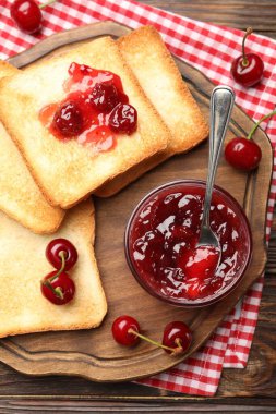 Lezzetli kiraz reçelli tostlar ve ahşap masada taze meyveler.