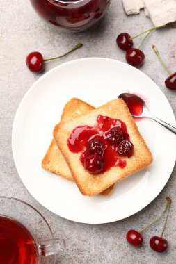 Lezzetli kiraz reçelli tostlar, çay ve gri masada taze meyveler, düz uzanma