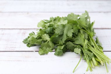 Beyaz ahşap masada taze aromatik kişniş, yakın plan.