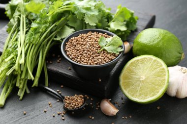 Koyu dokulu masada kişniş tohumları taze kişniş, kireç ve sarımsak, yakın plan.