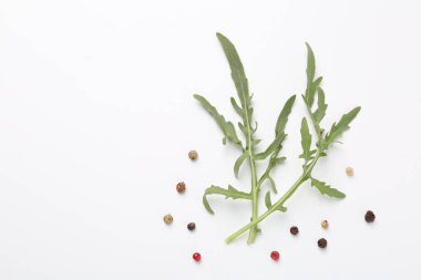 Taze yeşil roka yaprakları ve beyaz arka planda biberler, düz. Metin için boşluk