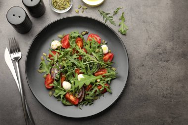 Lezzetli salata roka, mozzarella ve sebzeler gri masada servis edilir. Metin için boşluk