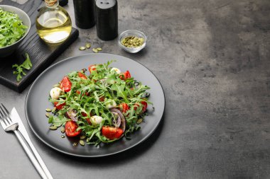 Lezzetli salata roka, mozzarella ve sebzeler gri masada servis edilir, yakın plan. Metin için boşluk