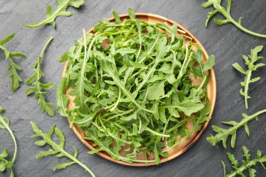 Taze yeşil roka yaprakları siyah masanın üzerinde, düz yatıyordu.