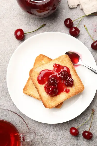 Lezzetli kiraz reçelli tostlar, çay ve gri masada taze meyveler, düz uzanma