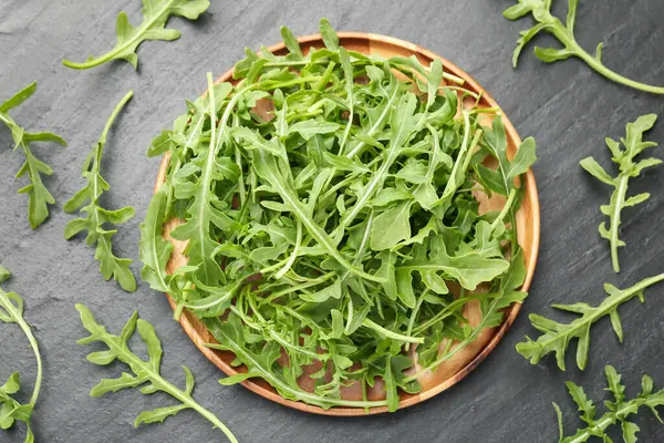 Taze yeşil roka yaprakları siyah masanın üzerinde, düz yatıyordu.