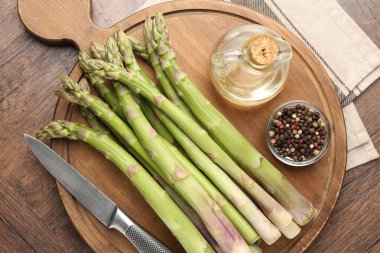 Taze çiğ kuşkonmaz, baharat, yağ ve bıçak ahşap masa, üst görünüm