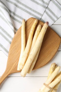 Beyaz ahşap masada çiğ kuşkonmaz mızrakları var.