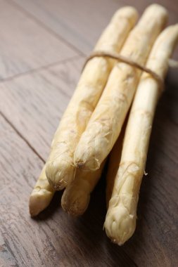 Ahşap masada çiğ beyaz kuşkonmaz mızrakları, yakın plan.