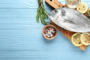 Mavi ahşap masa üzerinde baharatlı taze çiğ dourade balığı, düz ve metin için alan. Deniz ürünleri lezzetleri.