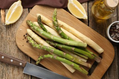 Farklı çiğ kuşkonmaz mızrakları, baharatlar ve bıçak ahşap masada, düz yatıyordu.