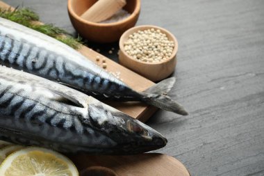 Deniz ürünleri lezzetleri. Siyah masada taze çiğ uskumrular ve baharatlar, yakın plan. Metin için boşluk