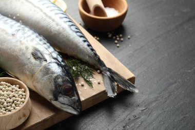 Deniz ürünleri lezzetleri. Siyah masada taze çiğ uskumrular ve baharatlar, yakın plan. Metin için boşluk