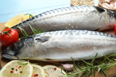 Açık mavi ahşap masada taze çiğ uskumrular ve baharatlar, yakın plan. Deniz ürünleri lezzetleri.