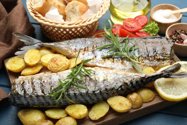 Baharat ve sebzelerle servis edilen kızarmış uskumrular mavi ahşap masada, yakın plan. Ev yapımı deniz ürünleri yemeği.