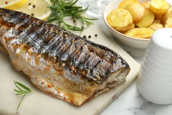 Beyaz mermer masada baharatlı ve patatesli kızarmış uskumru, yakın plan. Ev yapımı deniz ürünleri yemeği.