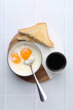Kâsede yarı haşlanmış yumurta, soya sosu ve beyaz fayanslı masada kızarmış ekmek. Geleneksel Asya kahvaltısı
