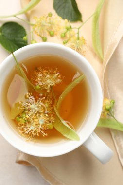 Taze ıhlamur çayı fincanda ve çiçekler beyaz masada, düz yerde.