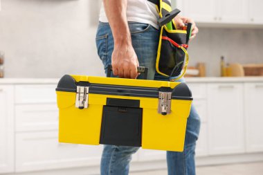 Kapalı mekanda alet çantası olan profesyonel bir tamirci.