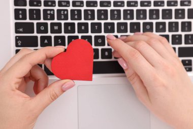 Online flört sitesi. Kalbi dekoratif olan bir kadın dizüstü bilgisayar kullanıyor.