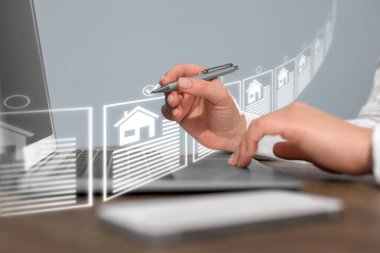 Emlakçı bilgisayarın üstündeki sanal ekranda evi seçiyor.