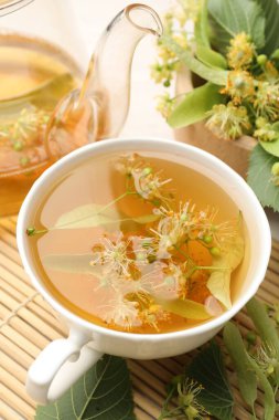 Taze ıhlamur çayı, çaydanlık ve çiçekler beyaz masada, yakın plan.