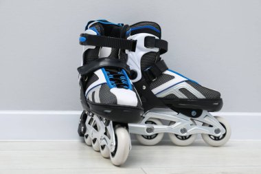 Beyaz duvarın yanında yerde bir çift paten var.