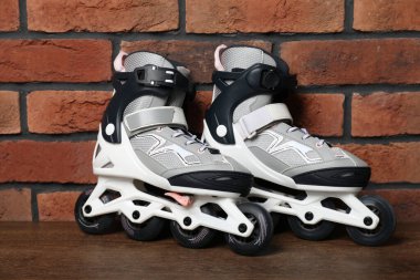 Tuğla duvarın yanındaki ahşap masada bir çift paten.