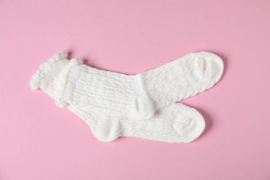 Pembe arka planda bir çift rahat beyaz çorap, üst manzara