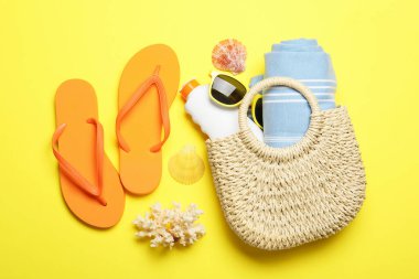 Plaj havlusuyla düz kompozisyon ve sarı arka planda diğer yaz aksesuarları.