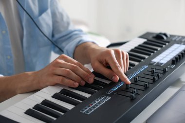İçerideki masada MIDI klavyesiyle çalışan adam, yakın plan.