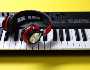 Sarı arka planda kulaklıklı MIDI klavyesi, yakın plan