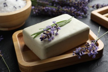 Aromatik sabun barı ve lavanta çiçekleri koyu dokulu masa üzerinde, yakın plan.