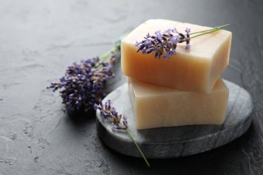 Aromatik sabun barları ve lavanta çiçekleri koyu dokulu masa üzerinde, yakın plan.