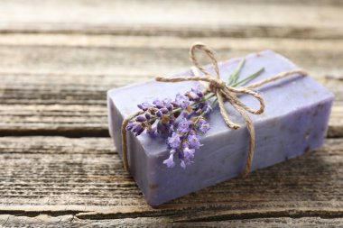 Aromatik sabun barı ve lavanta çiçekleri ahşap masada, yakın plan.