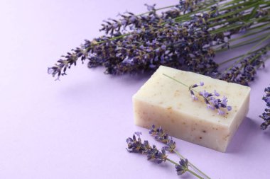 Aromatik sabun barı ve mor arka planda lavanta çiçekleri, yakın plan.