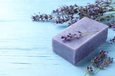 Aromatik sabun barı ve lavanta çiçekleri açık mavi ahşap masada, yakın plan. Metin için boşluk