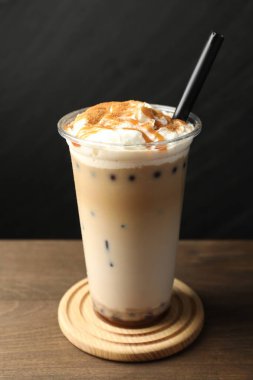 Tahta masada plastik bardakta lezzetli sütlü çay, yakın plan.